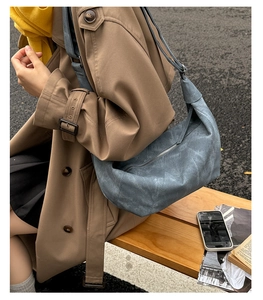 Detail of blue suede hobo bag with zipper and stitching in an outdoor street setting