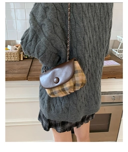 Retro plaid saddle bag with brown leather flap and silver chain worn by a model