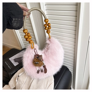 Detail of pink faux fur crescent handbag with wooden bead handle and plush charm