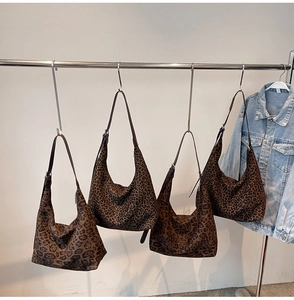 Detailed view of leopard print faux suede tote bags hanging on a display rack