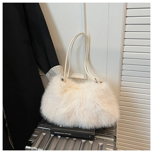 Close-up of fluffy cream faux fur tote bag with slim leather handles on a suitcase