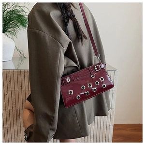 Detail view of burgundy patent leather bag with silver rivets and punk style buckle