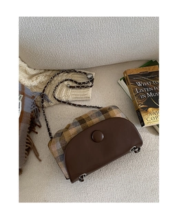 Detail of vintage saddle bag featuring retro plaid pattern and leather chain strap