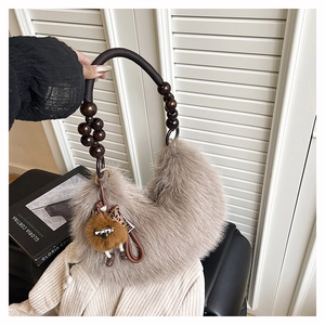 Close-up of fuzzy crescent hobo bag with vintage brown wooden beaded handle and plush charm