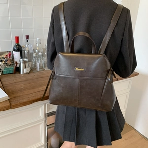 Close-up of retro brown faux leather backpack with gold buckle and adjustable straps
