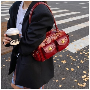 Close-up of vintage dark red leather pillow bag with gold hardware in street scene