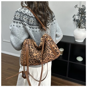 Detail shot of a leopard print tote bag with leather strap and silver metal lock pendant