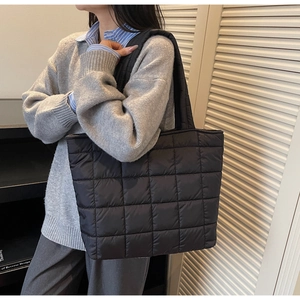 Close-up of lightweight black quilted puffer tote bag with classic square stitching detail
