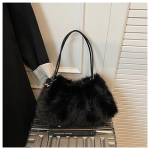 Detailed texture of black faux fur tote bag with leather handles on silver luggage