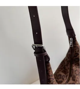 Close-up of adjustable brown leather shoulder strap and silver buckle on leopard tote