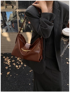 Détail du sac cabas en cuir verni marron avec boucle dorée en croissant et texture crocodile
