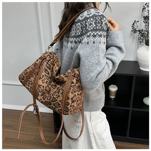 Detail view of the leopard print suede cylinder bag carried by a model in soft lighting