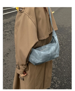 Detailed view of light blue moon-shaped shoulder bag with knot strap and zip closure