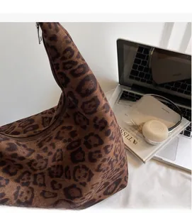 Leopard print tote bag detail showing suede material and zipper next to workspace items