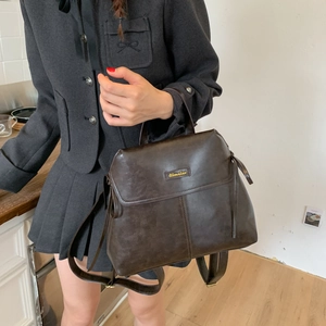 Close-up of vintage leather backpack with flap closure and top handle in dark brown