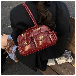 Detail of dark red vintage pillow bag with glossy finish and golden metal buckles