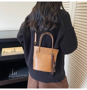 Detail shot of a brown leather bucket bag with tassels and adjustable shoulder strap