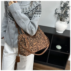 Detail shot of leopard print satchel bag featuring brown leather trim and metal hardware