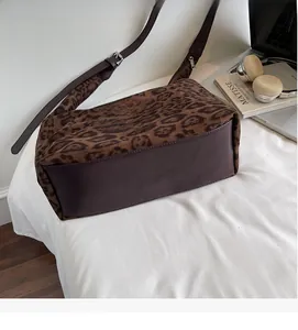 Detail of leopard print suede bag showing the leather bottom and adjustable strap texture