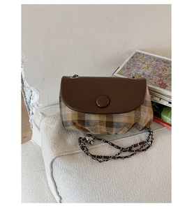 Detail of retro saddle bag featuring brown leather flap and stylish plaid fabric texture