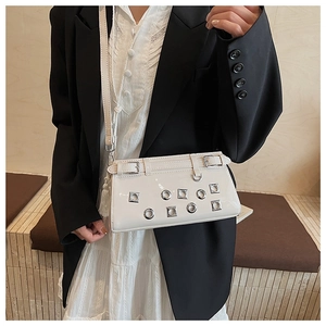 Detail of white patent leather crossbody bag with silver studs and tassel accessories