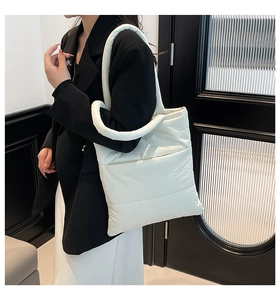 Close-up of quilted puffer tote bag with thick circular handles on model