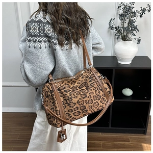 Detailed back view of a leopard print tote bag featuring brown leather straps and a metal padlock
