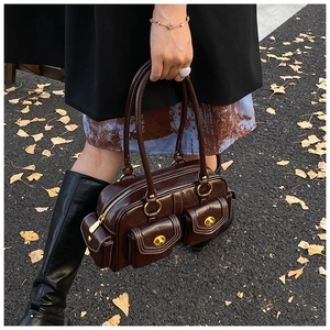 Macro detail of dark brown glossy leather handbag with golden twist locks on autumn street