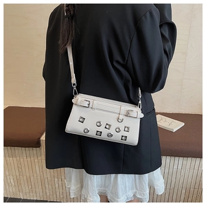 Detail of white studded crossbody bag with silver eyelets and punk style buckle