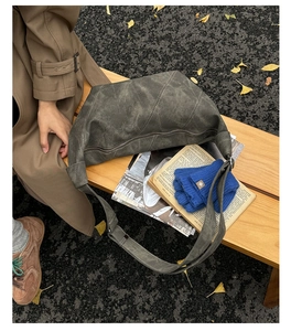 Detail of vintage gray textured leather crossbody bag on park bench with autumn leaves