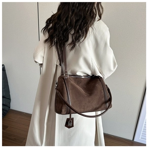 Detail of a dark brown suede shoulder bag featuring a vintage padlock and leather strap