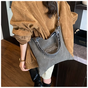 Detail of grey suede tote bag with silver metal art lettering and stud handle accents
