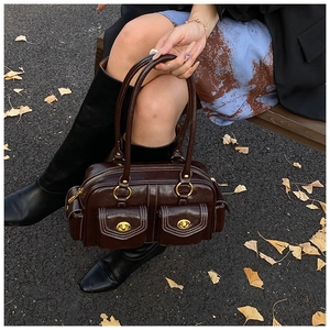 Close-up of vintage brown leather pillow bag with gold turn-locks and contrast stitching