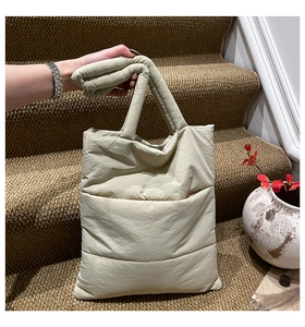 Detailed view of beige quilted tote bag texture and soft padded handle details