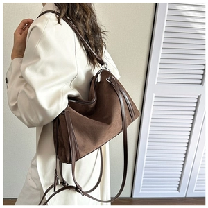 Brown faux suede tote bag with leather strap worn by a woman in a white coat