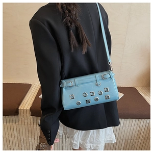 Detail showing the light blue patent leather crossbody bag worn by a model in black suit