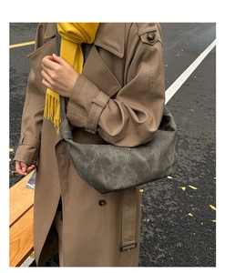 Detail shot of a dark grey hobo bag with contrast stitching on a street style model