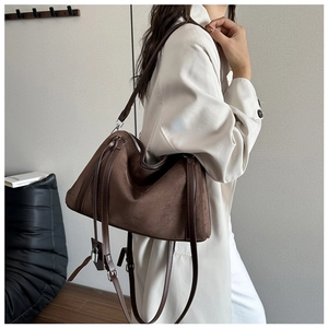 Detailed close-up of brown suede tote bag with zipper closure and metal lock charm