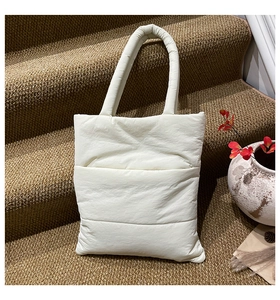 Detail of white quilted tote bag with padded handles on a staircase setting