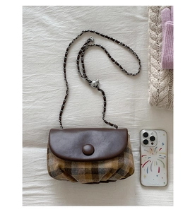 Detail of vintage plaid saddle bag with mixed leather materials and chain strap