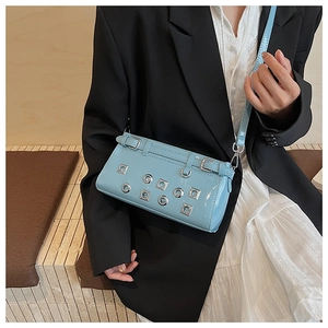 Detail of light blue patent leather shoulder bag featuring silver metal eyelets and studs