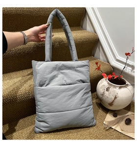 Detail view of grey quilted puffer tote bag with thick padded handles for winter