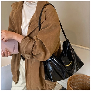 Vue latérale d'un sac hobo noir brillant avec une élégante boucle dorée en métal
