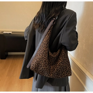 Model wearing a large leopard print tote bag with brown leather strap in a retro style