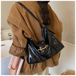 Détail du sac hobo en cuir verni noir avec boucle croissant dorée et texture plissée