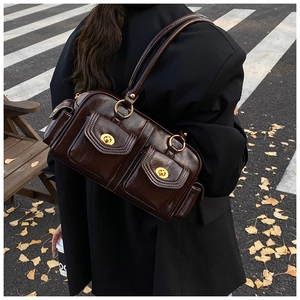 Close-up of vintage brown shoulder bag with dual gold twist-lock pockets and white stitching