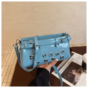 Detail of light blue patent leather handbag with metal eyelets and adjustable strap
