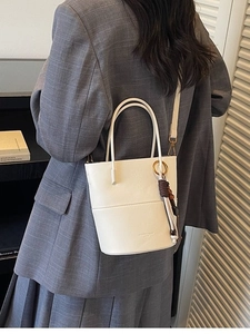 White leather bucket bag with woven bead charm and shoulder strap for commute