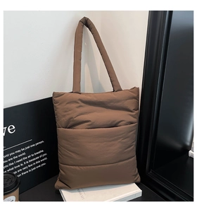 Detail of a dark brown quilted puffer tote bag in a stylish urban lifestyle setting