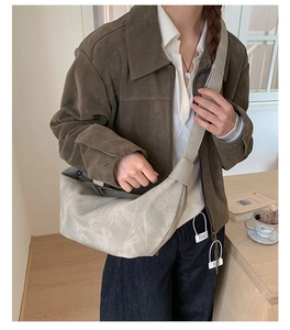 Detailed view of off-white faux suede crescent bag with wide shoulder strap in daily setting